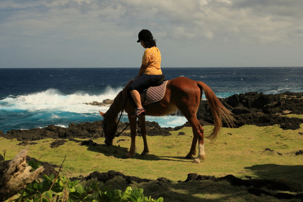 Cavalière au bord des vagues sur la côte de lave de Saint-Philippe