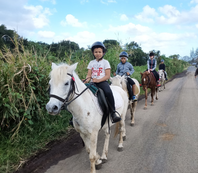 Groupe d'enfants à poney sur une route de Saint-Philippe